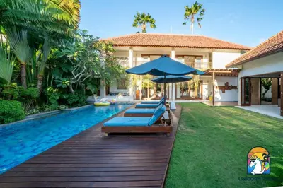 a pool with lounge chairs and an umbrella next to a house at Villa Kajou - by Unicorn Villas Bali in Seminyak