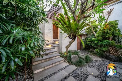 a set of stairs with a palm tree in a garden at Villa Kajou - by Unicorn Villas Bali in Seminyak