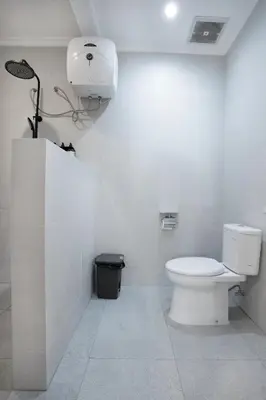 a white bathroom with a toilet and a light at Villa Isla Bali in Seminyak