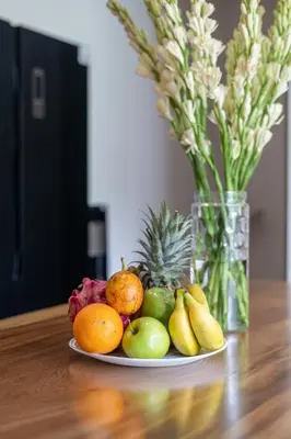 a plate of fruit on a table with a vase of flowers at Ami villa in the heart of Canggu in Canggu