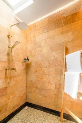 a bathroom with a shower with a wooden wall at Ami villa in the heart of Canggu in Canggu