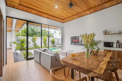 a dining room and living room with a wooden table at Ami villa in the heart of Canggu in Canggu