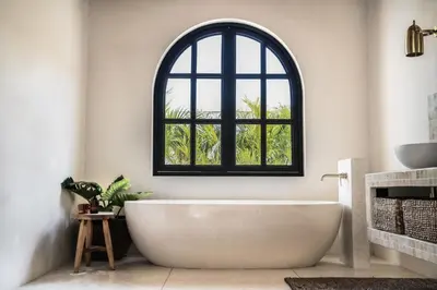 an arched window in a bathroom with a white tub at Villa Almaz Seminyak in Seminyak