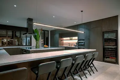 a kitchen with a long counter with chairs in it at CARPEDIEM VILLA BALI operated by Villa Nila in Canggu