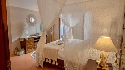 a bedroom with a canopy bed and a table with a lamp at Leluhur 2 - 3BR, Free Nmax, Airport Pick Up and YT Premium in Seminyak