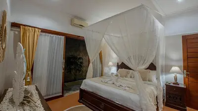 a bedroom with a canopy bed with white curtains at Leluhur 2 - 3BR, Free Nmax, Airport Pick Up and YT Premium in Seminyak