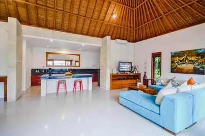 a living room with a blue couch and a kitchen at Minara 4 BR Private Pool Villa in Canggu