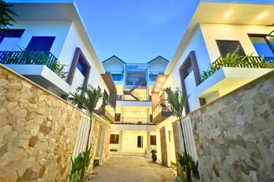 a large white building with palm trees in front of it at Reline 1 BR Studio with Sofa Bed in Jimbaran