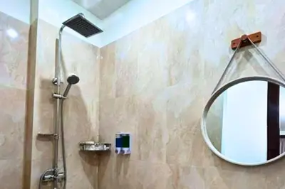 a bathroom with a shower with a round mirror at Reline 1 BR Studio with Sofa Bed in Jimbaran