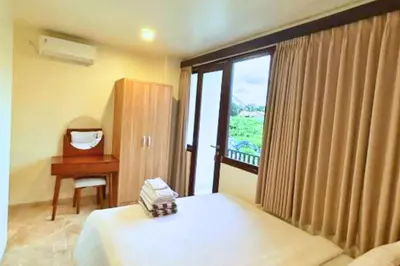 a bedroom with a bed and a desk and a window at Anyaa 3 BR Apartment in Jimbaran
