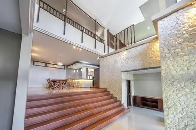 a staircase in a house with a dining room and a table at Aradhia Villa Nusa Dua in Nusa Dua