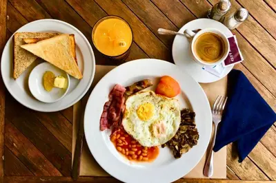 a table with two plates of breakfast food and a cup of coffee at Camana 1 BR Villa With Shared Pool in Canggu