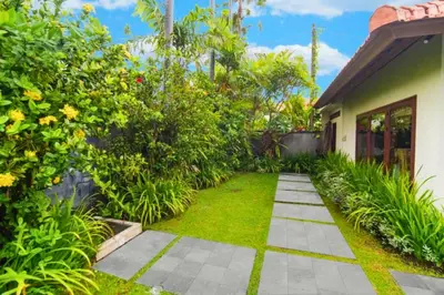 a garden with a walkway next to a house at Camana 1 BR Villa With Shared Pool in Canggu