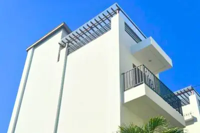 a white building with a balcony on the side of it at Willy 4 BR Comfort Quadruple Room in Jimbaran