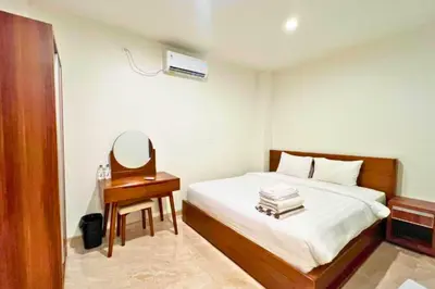 a bedroom with a bed and a table with a mirror at Willy 4 BR Comfort Quadruple Room in Jimbaran