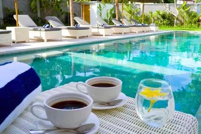 two cups of coffee on a table next to a pool at Narasnama 6 BR Private Pool Villa in Canggu