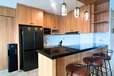 a kitchen with a black refrigerator and wooden cabinets at Abimana 5 BR Presidential Suite Private Pool in Jimbaran