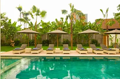 a swimming pool with lounge chairs and umbrellas at Nawasena 5 BR Private Pool Villa in Canggu