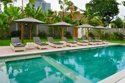 a swimming pool with lounge chairs and umbrellas at Nawasena 5 BR Private Pool Villa in Canggu