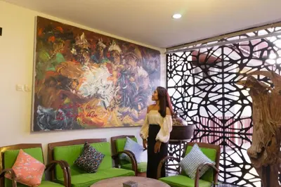 a woman standing in front of a large painting at Hadi Poetra Hotel in Kuta
