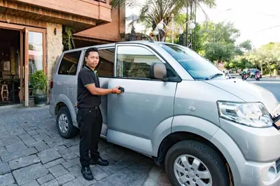 a police officer standing next to a silver vehicle at Hadi Poetra Hotel in Kuta