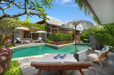 a pool with a table and chairs and an umbrella at Villa Gahana Bali in Seminyak