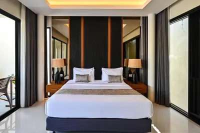 a bedroom with a large bed with two lamps at The Cabana Villa in Seminyak