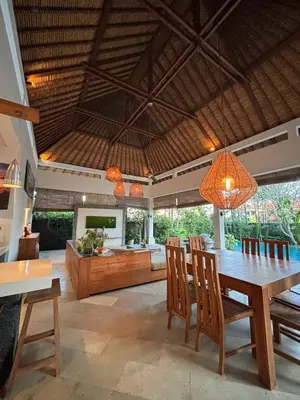 a dining room and living room with a table and chairs at Villa Jepun in Canggu