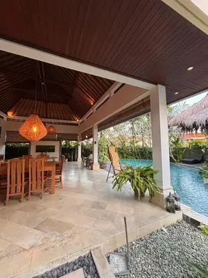 a patio with a table and chairs and a pool at Villa Jepun in Canggu