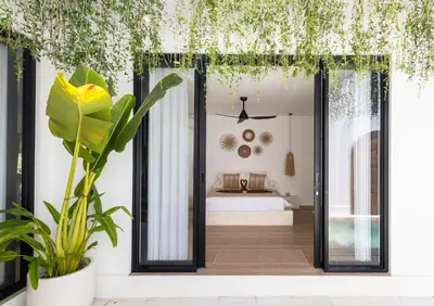 a bedroom with a bed in a room with plants at New Villa Manis proche Seminyak in Seminyak