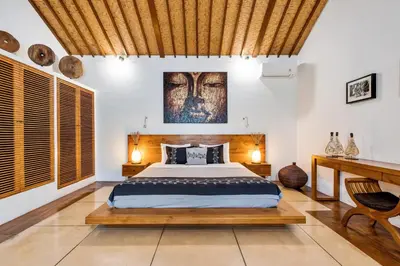 a bedroom with a bed with a wooden headboard at Villa Shantika by Villa Finder in Seminyak