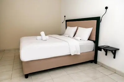 a bed with white sheets and pillows in a room at Villa Majapahit Kuta 5 bedrooms in Legian