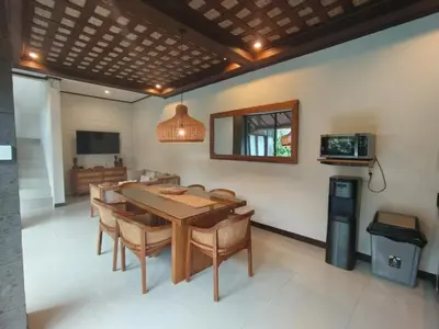 a dining room with a table and chairs and a television at Villa CUCU - Legian - 3 Bedroom in Legian