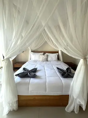 a bedroom with a white bed with white curtains at Villa CUCU - Legian - 3 Bedroom in Legian