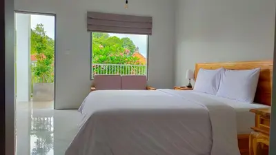 a bedroom with a white bed and a large window at Aleenka House in Canggu