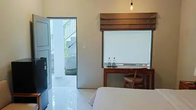 a bedroom with a bed and a desk and a window at Aleenka House in Canggu
