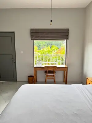 a bedroom with a bed and a window with a chair at Aleenka House in Canggu