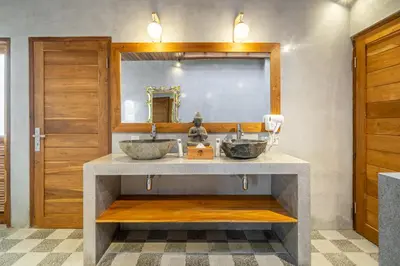 a bathroom with two sinks and a mirror at The Secret Jungle Villas Seminyak in Seminyak