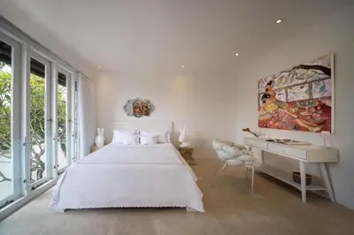 a white bedroom with a white bed and a desk at Villa Manis Cantik in Seminyak