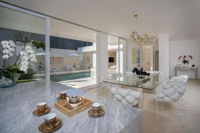 a living room with a glass table and white chairs at Villa Manis Cantik in Seminyak