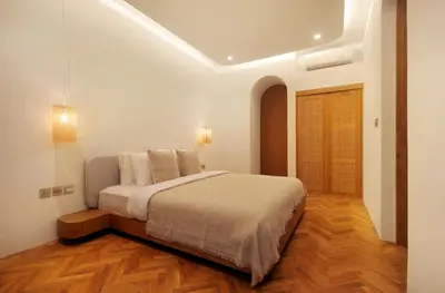 a white bedroom with a bed and a wooden floor at Jipsi Villas Canggu in Canggu