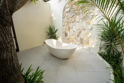 a bath tub sitting in a room with a stone wall at Villa Coconut Heaven by Bali Villa Solutions in Seminyak