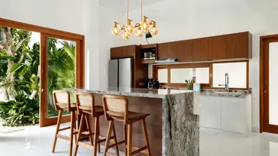 a kitchen with a counter with chairs and a island at Villa Latima by Villa Finder in Seminyak