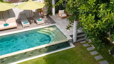 an overhead view of a pool with chairs and an umbrella at Villa Latima by Villa Finder in Seminyak