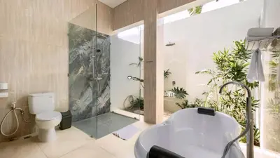 a bathroom with a shower and a toilet and a tub at Villa Latima by Villa Finder in Seminyak