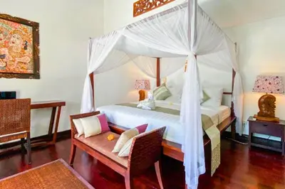 a bedroom with a canopy bed with a table and a chair at Chandani 3 BR Private Pool Villa in Ujung
