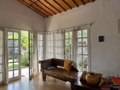 a living room with a bench and large windows at Cottage House Jimbaran in Jimbaran