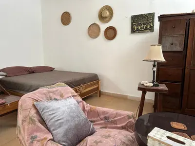 a bedroom with a bed and a couch and a chair at Cottage House Jimbaran in Jimbaran