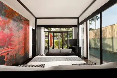 a bedroom with three beds and a large window at Shanti Estate Seminyak by Nakula in Seminyak