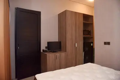 a bedroom with a bed and a cabinet with a television at MINI Coliving Apartment in Seminyak
